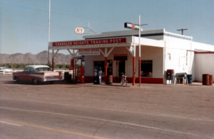 White building with white trim, gas pumps and mail collection box, sign Chandler Heights Trading Post and US Post Office