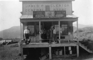 Black and white photo of people standing outside a building on stilts; signage James P. Cleator General Store Turkey Post Office