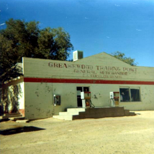 Old white building with gas pumps and pay phone outside; painted on front: Greasewood Trading Post General Merchandise