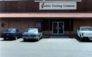 Exterior of building and parking lot with vehicles and Pepsi machine; signage: Kaibito Trading Company